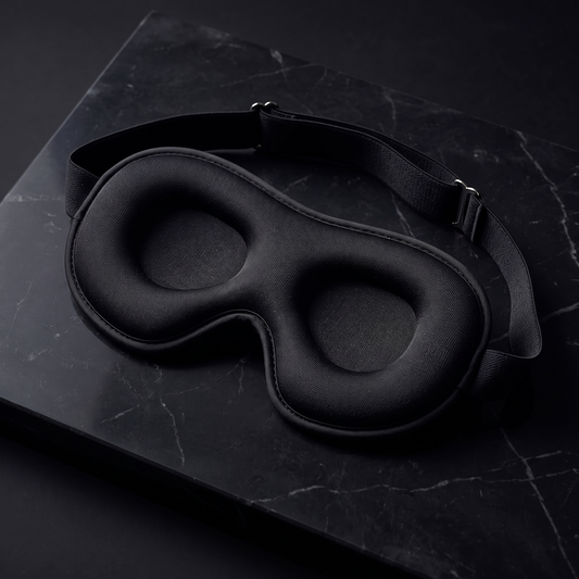 Black 3D contoured sleep mask on dark marble