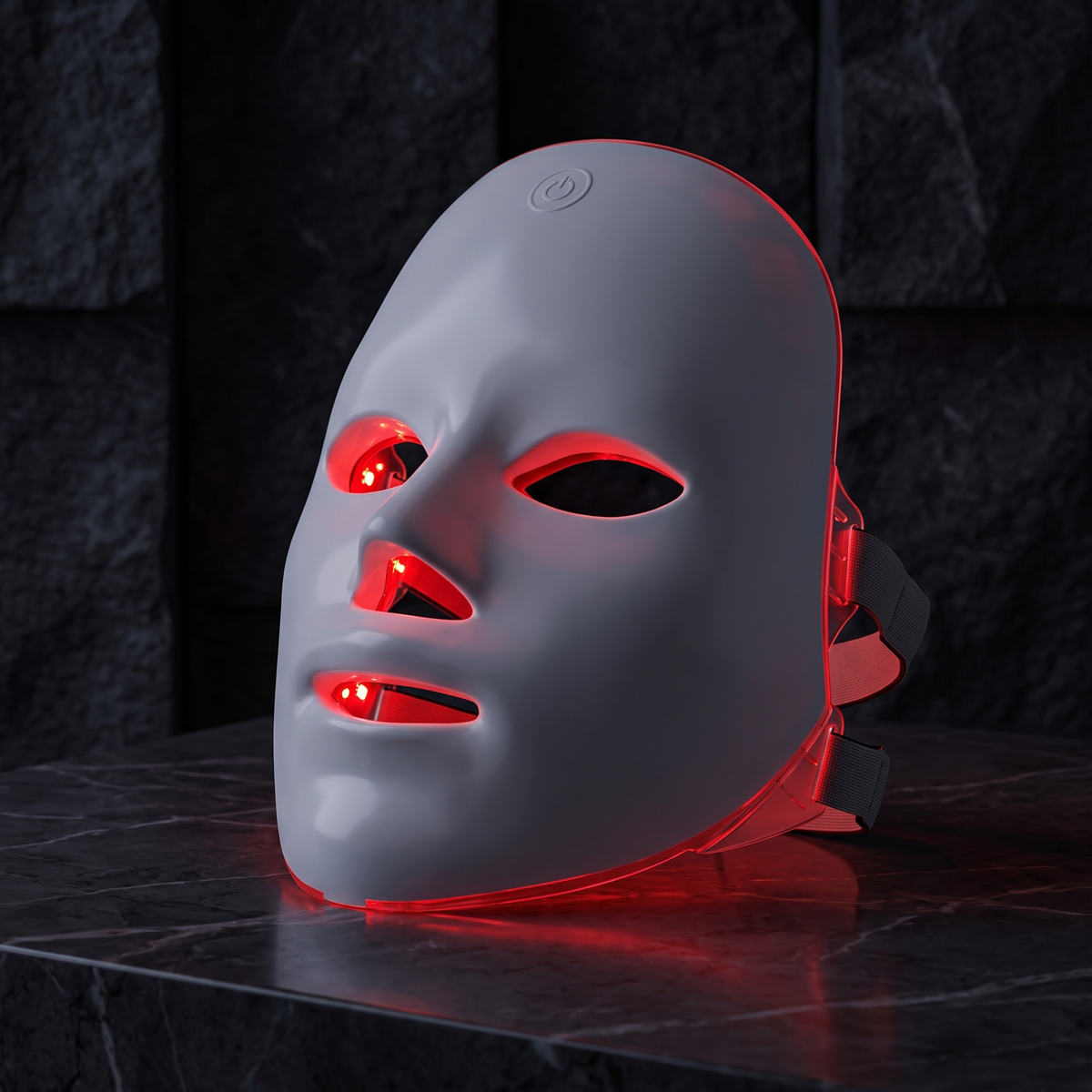 LED face mask glowing red on dark marble