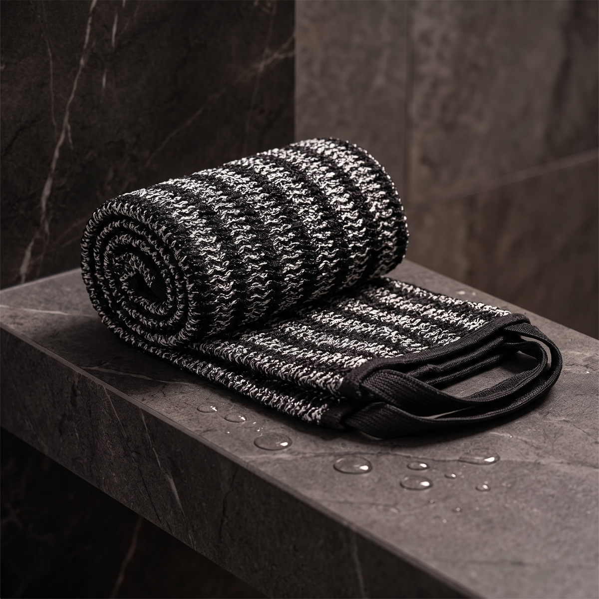 Exfoliating back scrubber towel on a dark stone ledge